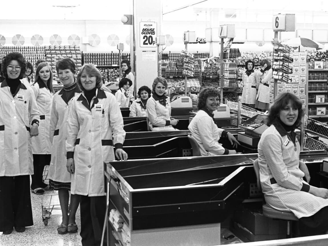 Equipe do Supermercados Guanabara nos caixas de uma loja, em foto de época